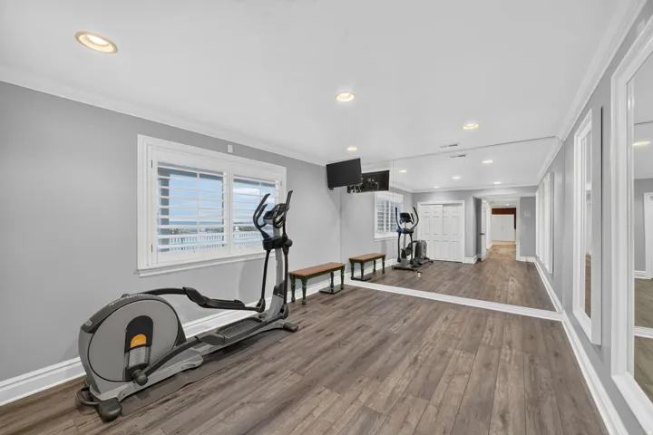 Recessed lighting, wood-finish flooring, full-length wall mirrors, windows with plantation shutters, and crown molding