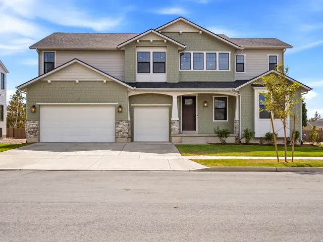 Contemporary two-story residence with a multi-tone exterior, featuring a two-car garage, a single-car garage, and a covered porch entry