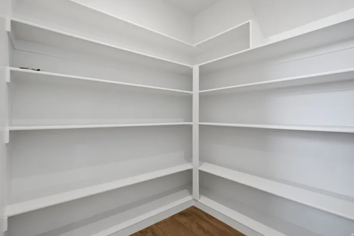 Corner pantry featuring extensive white shelving