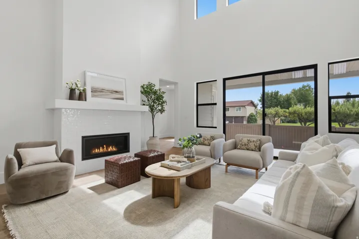 Two-story ceilings with expansive windows and upper transom windows, linear fireplace with white tile surround, and LVP flooring