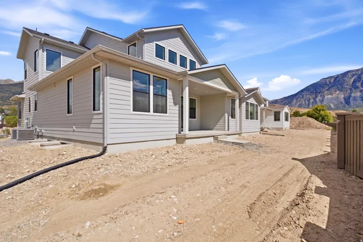 Multi-level residence featuring light gray siding, multiple gables, a covered front porch, and black-framed windows