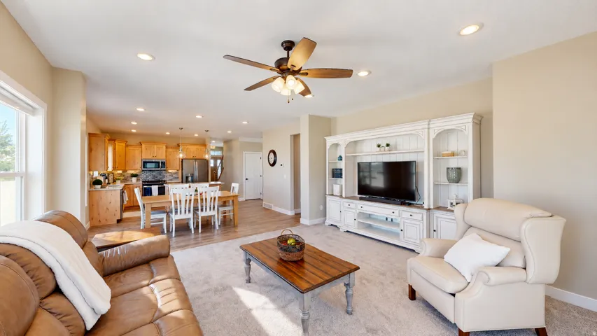Open-concept living space with a ceiling fan, recessed lighting, and light-toned carpeting