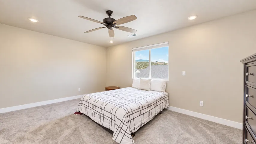 Recessed lighting, ceiling fan, neutral wall paint, carpeted flooring, and a large window