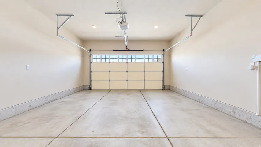 Attached garage with a concrete floor, automatic door opener, and recessed lighting