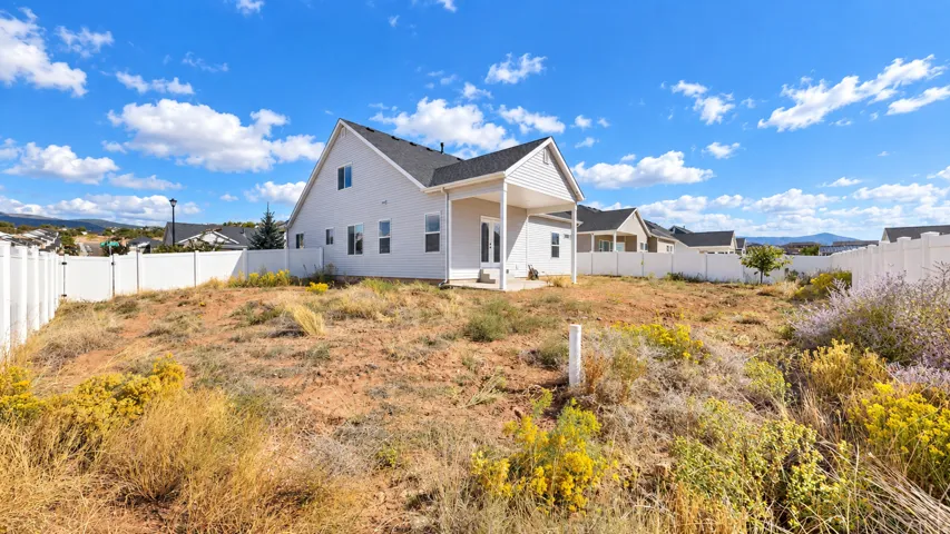 Expansive lot featuring a full-height vinyl privacy fence, covered patio, and distant mountain scenery