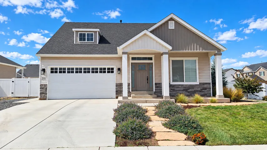 Contemporary exterior with a covered porch, stone veneer accents, an attached garage, and a concrete driveway