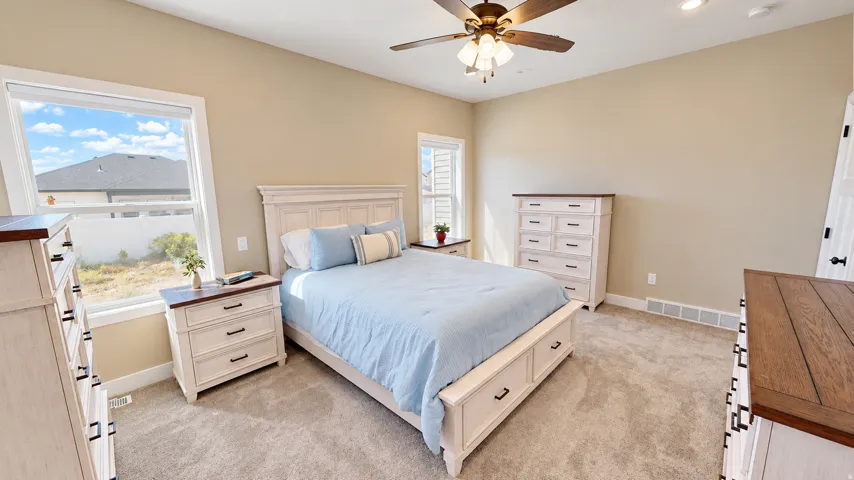 Carpeted flooring with neutral wall tones and a ceiling fan with integrated lighting