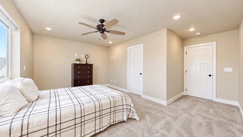 Recessed lighting, ceiling fan with wood-finish blades, and neutral-toned carpeting