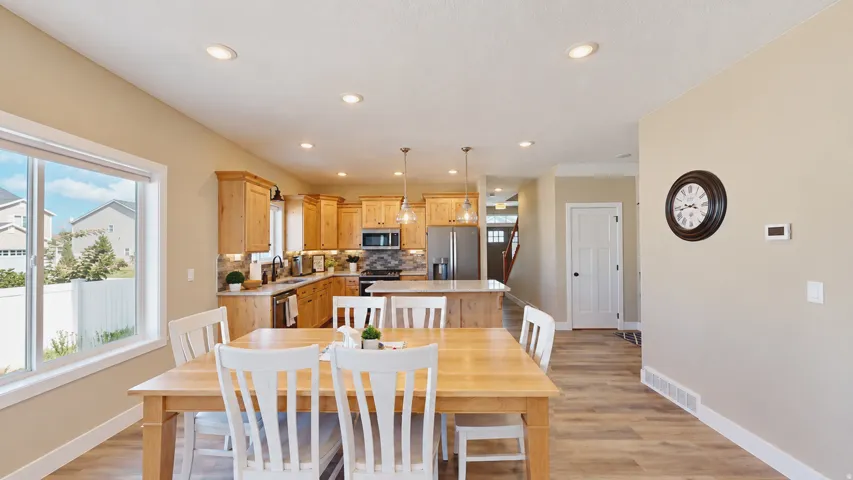Open-concept living space with wood-finish flooring, recessed lighting, and a window with white trim