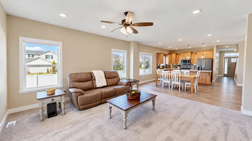 Open concept living area with carpeting, recessed lighting, ceiling fan, and multiple windows