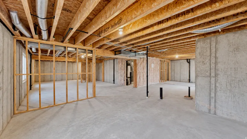 Unfinished basement featuring concrete walls and flooring, exposed ceiling joists, wood framing, and visible utility lines