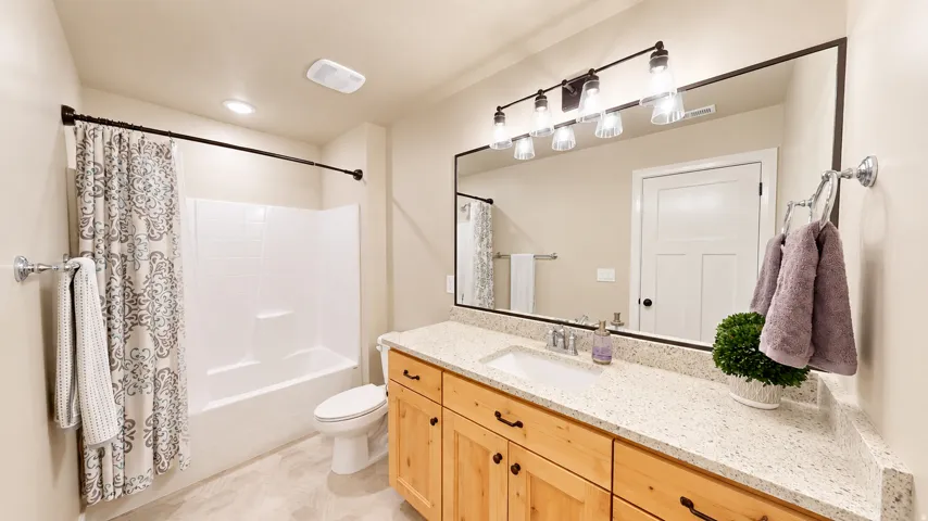 Extended vanity with a light-toned countertop, integrated sink, and an expansive framed mirror