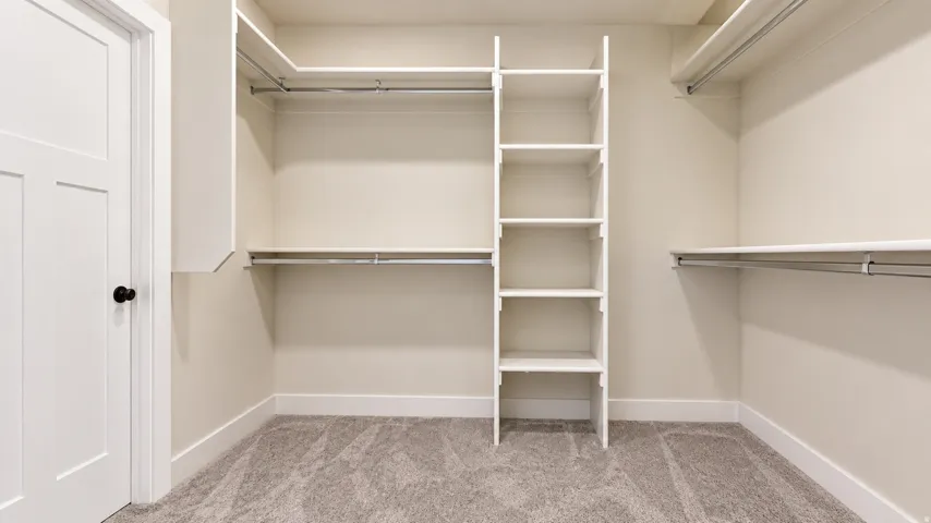 Walk-in closet with built-in shelving, multiple hanging rods, and neutral carpet