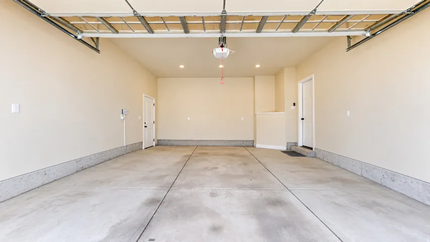 Spacious garage with concrete flooring, two access doors, and recessed lighting