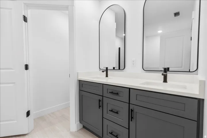 Dual vanity with gray cabinetry, integrated sinks, white countertops, and black fixtures