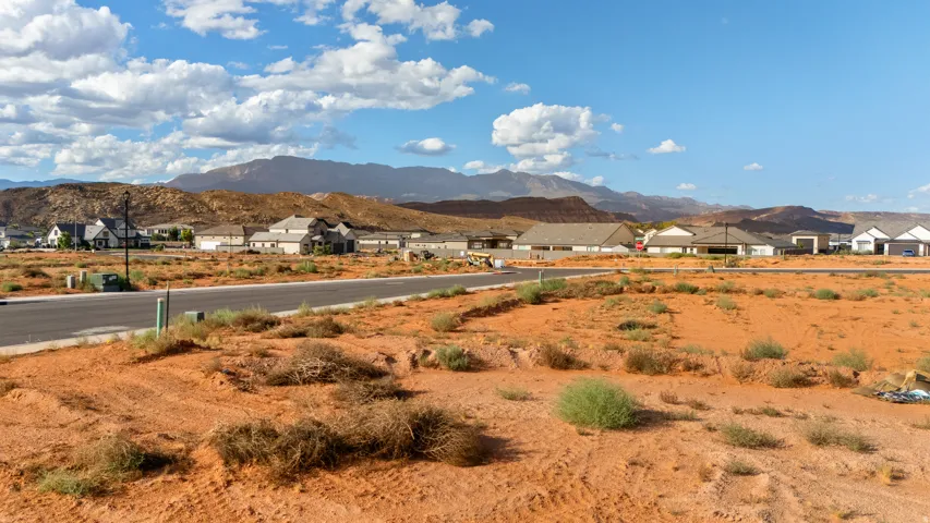 Expansive desert lot featuring red earth and distant mountains