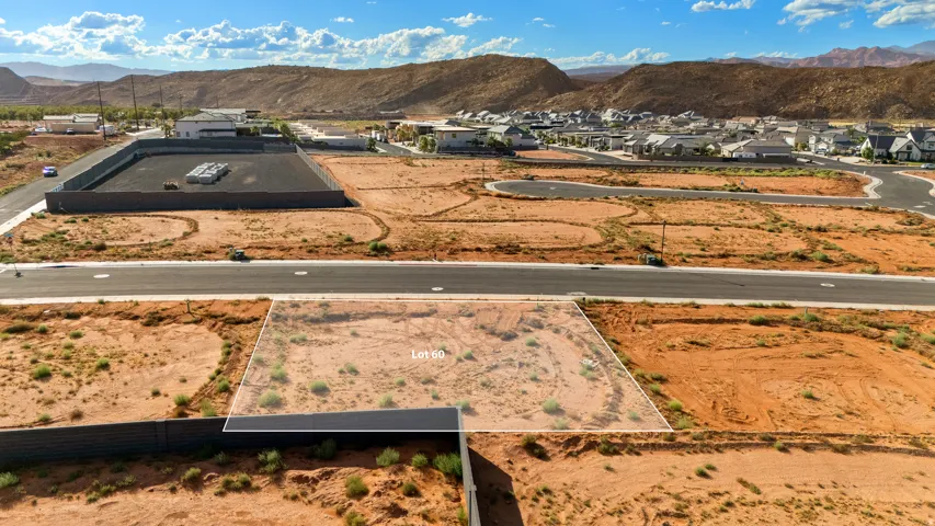 Cleared land parcel with a partial perimeter fence, bordered by paved roads