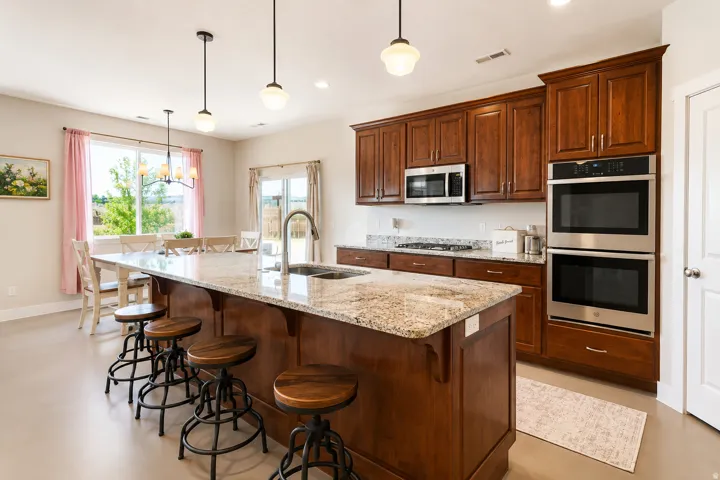 Expansive kitchen island featuring a granite countertop, integrated sink, and pendant lighting