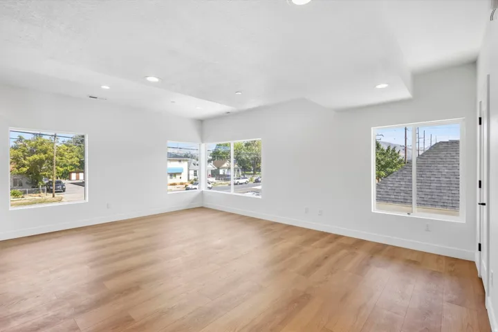 Spacious room featuring wood-finish flooring, recessed lighting, multiple windows, and a vaulted ceiling