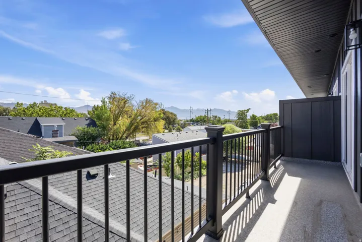 Balcony with dark metal railing, gray exterior siding, and a mountain backdrop