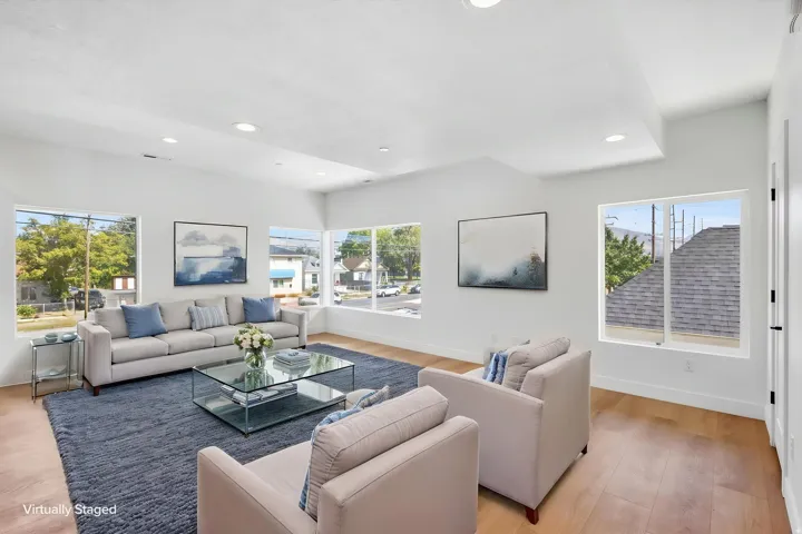Vaulted ceilings with recessed lighting, light wood-finish flooring, white walls, and multiple large windows