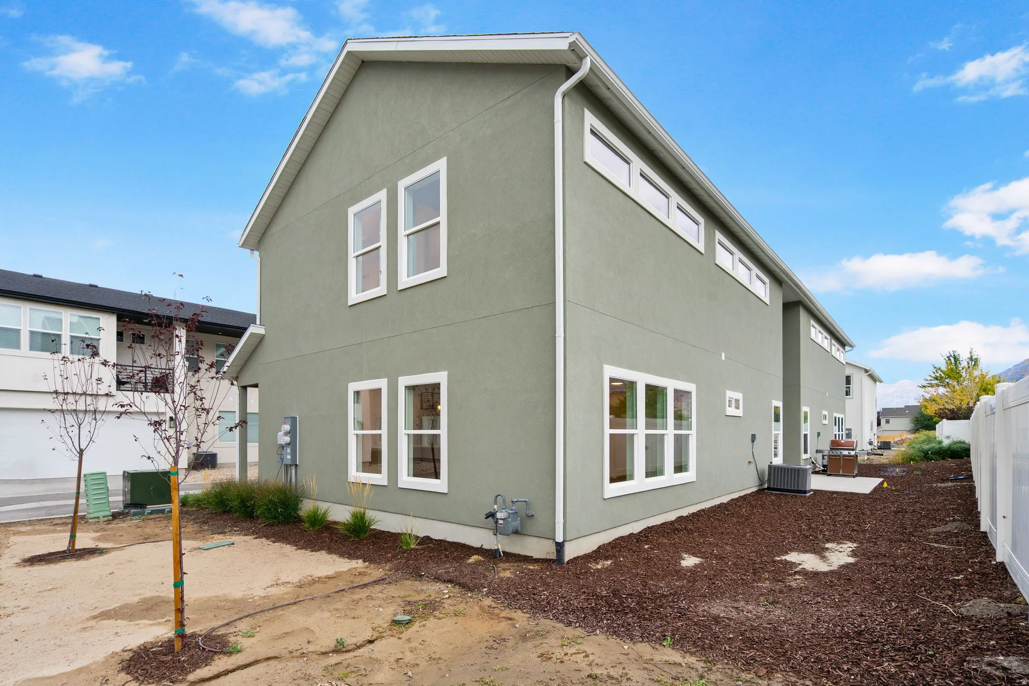Contemporary exterior with light green stucco finish, white trim, and multiple windows
