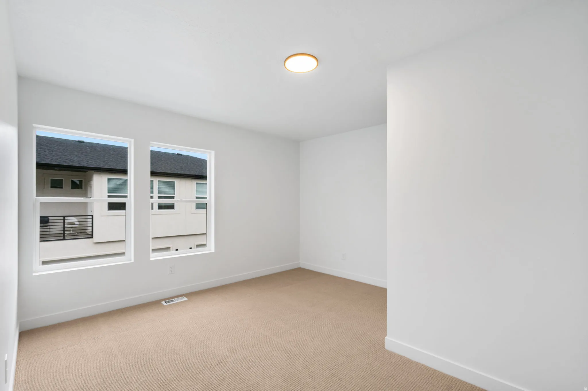 White interior walls, two large rectangular windows, and a flush-mount ceiling light fixture