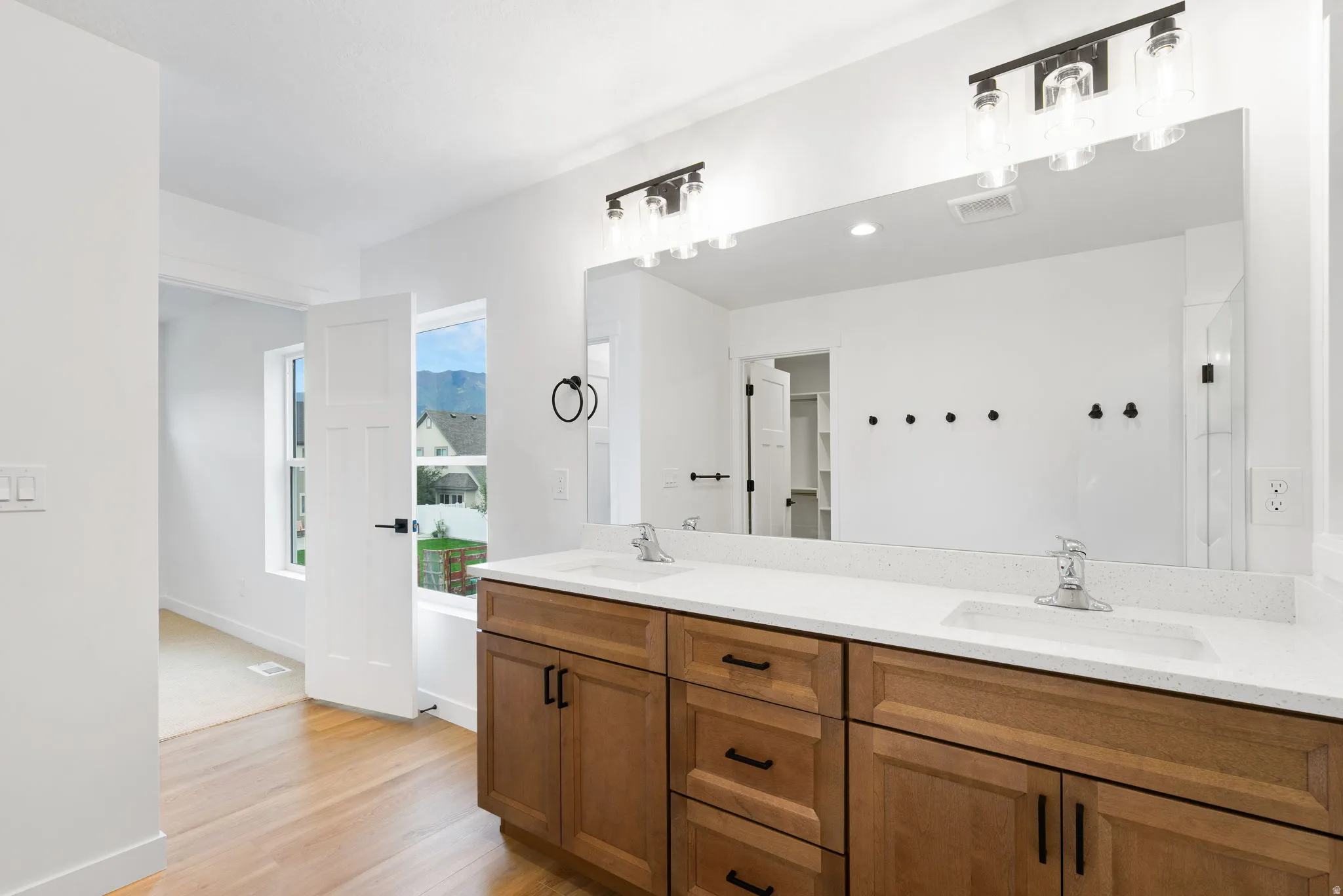 Dual vanity featuring a light-toned wood finish, white countertop, and rectangular undermount sinks