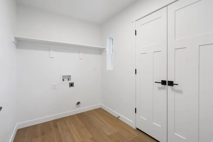 Wood-finish flooring, white walls, built-in shelving, panel doors with matte black hardware, and an integrated window