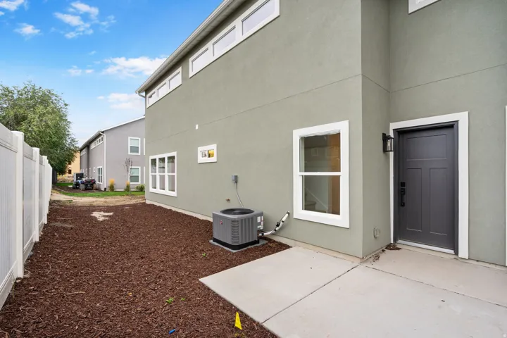 Stucco exterior with white-framed windows, a dark panel door, and a wall-mounted exterior light fixture