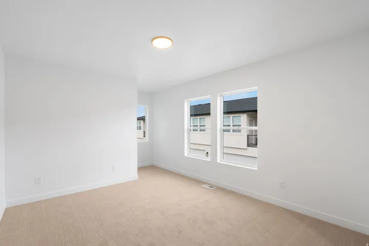Recessed lighting, three windows providing natural light, neutral carpeting, and white wall finishes