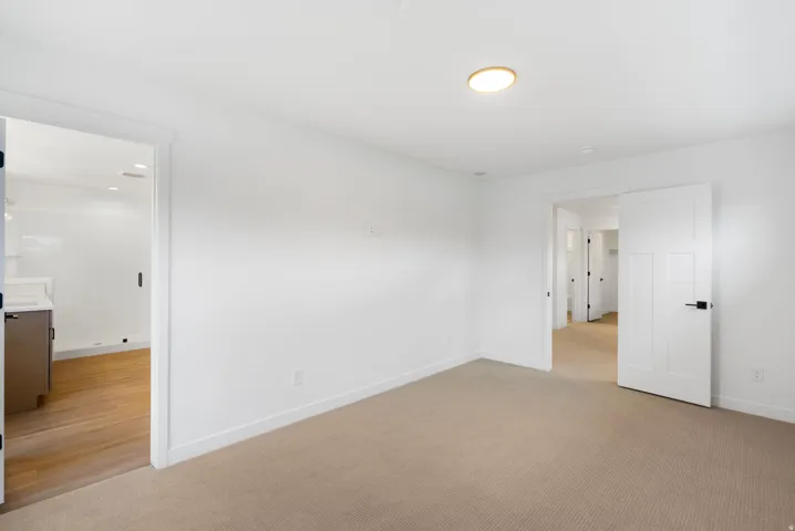 Neutral-toned carpeting, white walls, and a contemporary ceiling light fixture