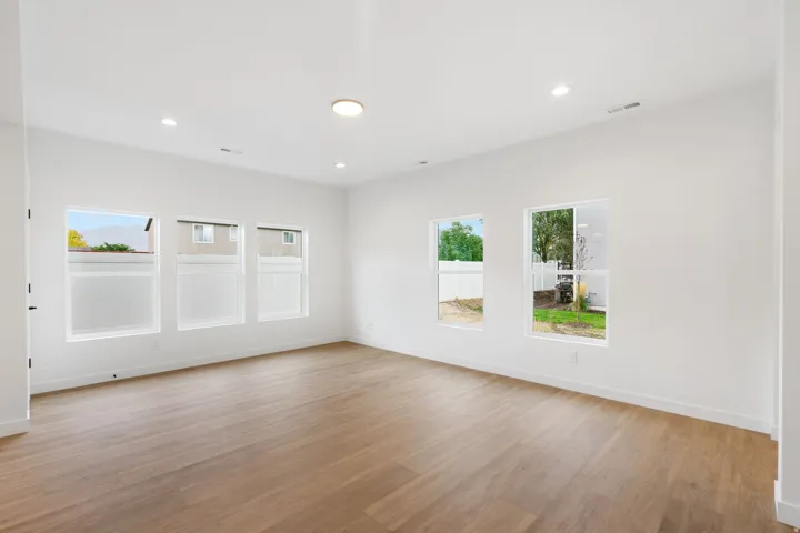 White walls, wood-finish flooring, recessed lighting, and multiple windows