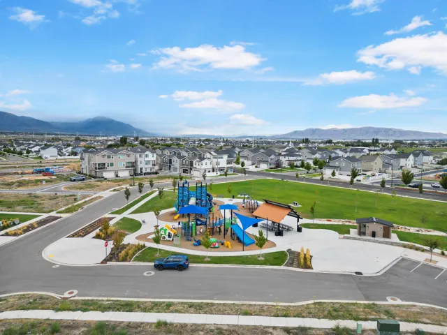 Community park with playground structures, open green space, paved pathways, and a covered pavilion