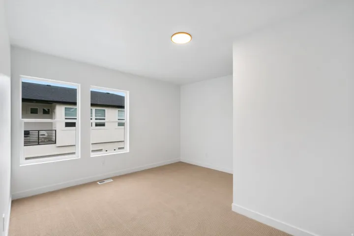 White interior walls, two large rectangular windows, and a flush-mount ceiling light fixture