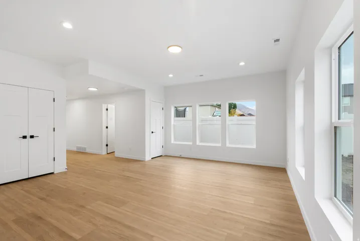 Recessed lighting, wood-finish flooring, white walls, multiple windows, and crisp white trim