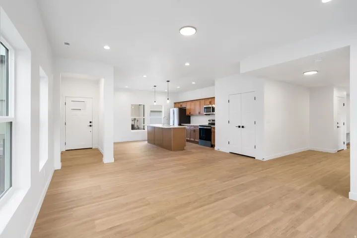 Open-concept living space featuring wood-finish flooring, recessed lighting, a kitchen island, and stainless steel appliances