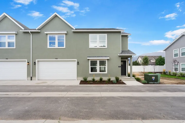 Contemporary stucco exterior with white-framed windows, attached two-car garage, covered entry, and low-maintenance landscaping