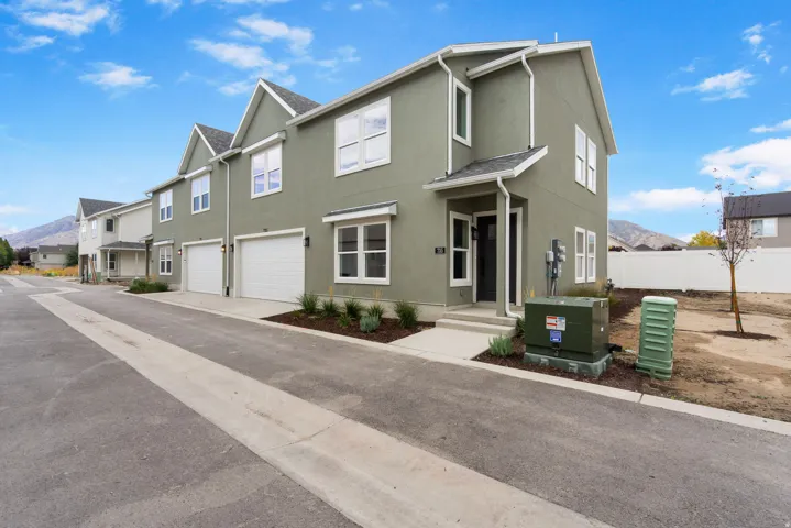 Modern townhome design featuring a stucco exterior, gabled rooflines, and white-framed windows