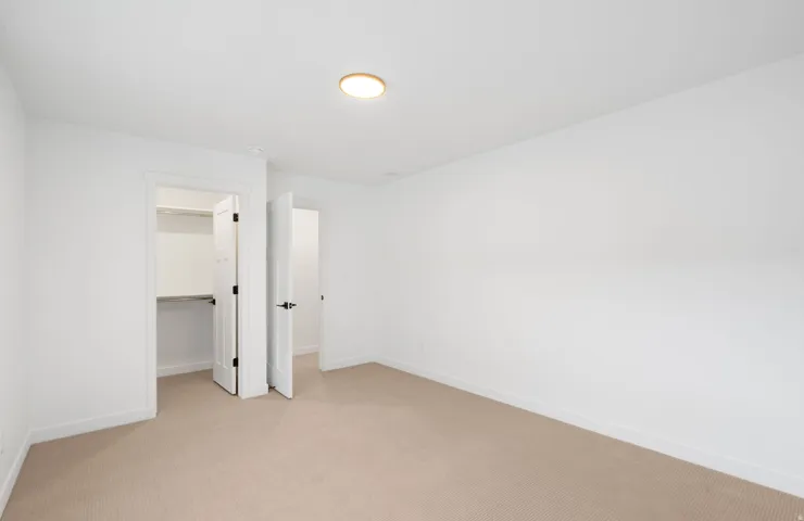 Neutral-toned carpet flooring, white walls, and a flush-mount ceiling fixture