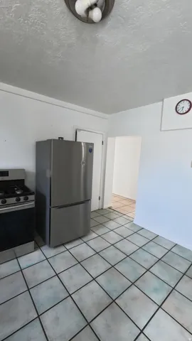 Stainless steel refrigerator, stainless steel range, tile flooring, flush mount ceiling fixture, painted walls