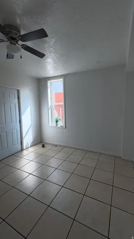 Tile flooring, white paneled door, single window, and a ceiling fan with integrated lighting