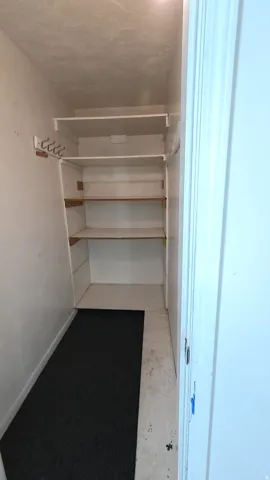 Built-in shelving with wood-finish supports and wall-mounted hooks