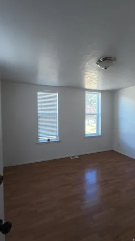 Wood-finish flooring with white walls, two windows, and a flush-mount ceiling light fixture