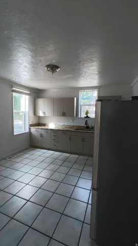 Kitchen featuring light cabinetry, a dark sink, light-colored countertops, tile flooring, and a ceiling-mounted light fixture