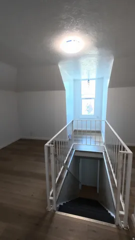 Wood-finish flooring, white painted walls, recessed window, white metal railings, and overhead lighting