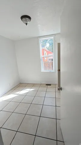 Ceramic tile flooring, neutral wall finishes, single window, and a flush-mount light fixture