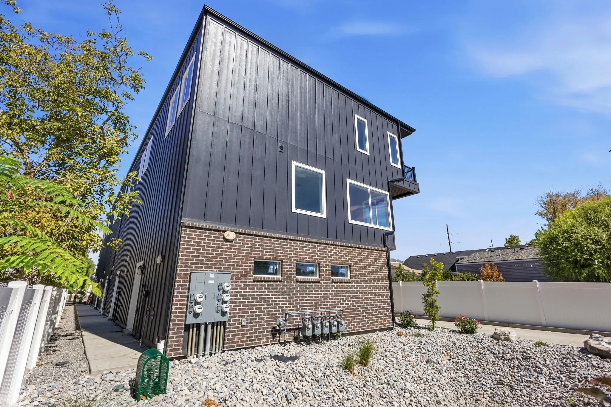 Contemporary exterior featuring dark vertical siding and brick accents