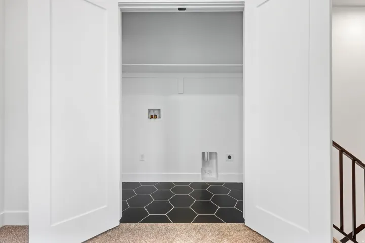 Built-in laundry hookups with hexagon floor tiling and upper shelving
