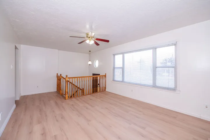 Wood-finish flooring, white walls, and a large multi-pane window with blinds